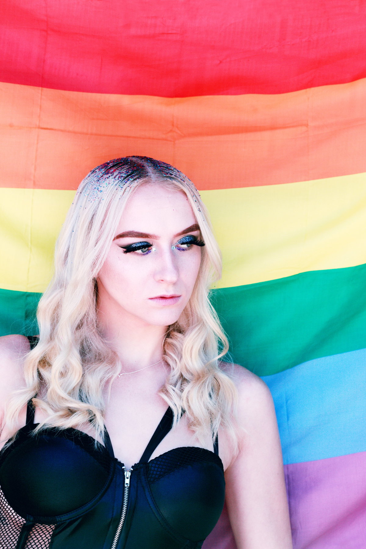 Blonde Person vor Regenbogen Flagge