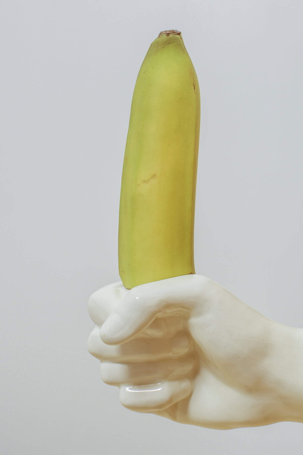 Porzellanhand, die eine Banane greift