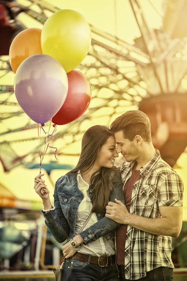 Mädchen und Junge vor Riesenrad mit Luftballons
