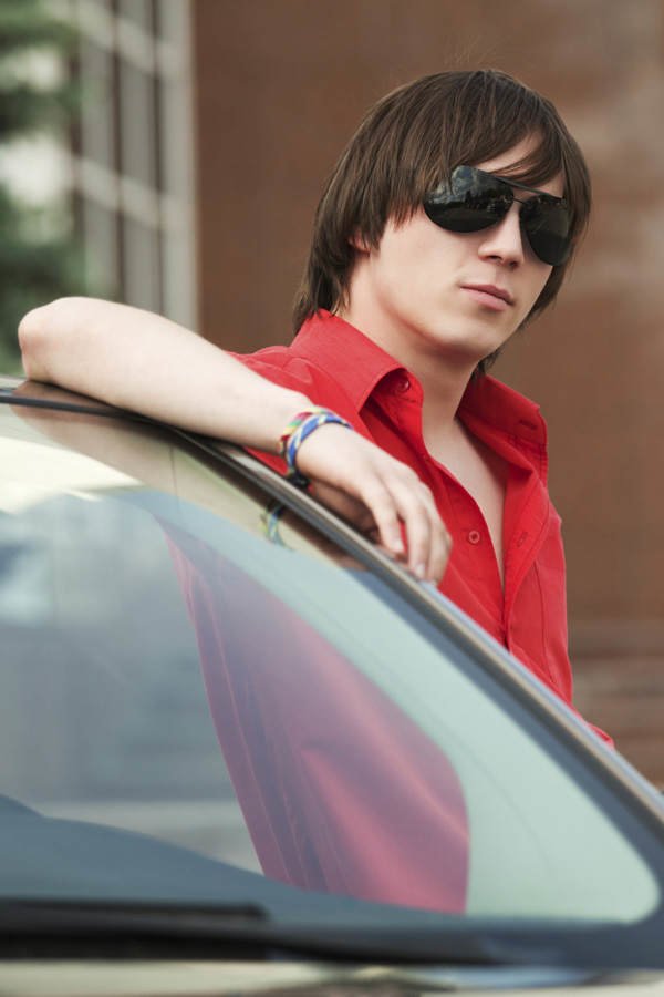 Junge mit Sonnenbrille an Auto gelehnt