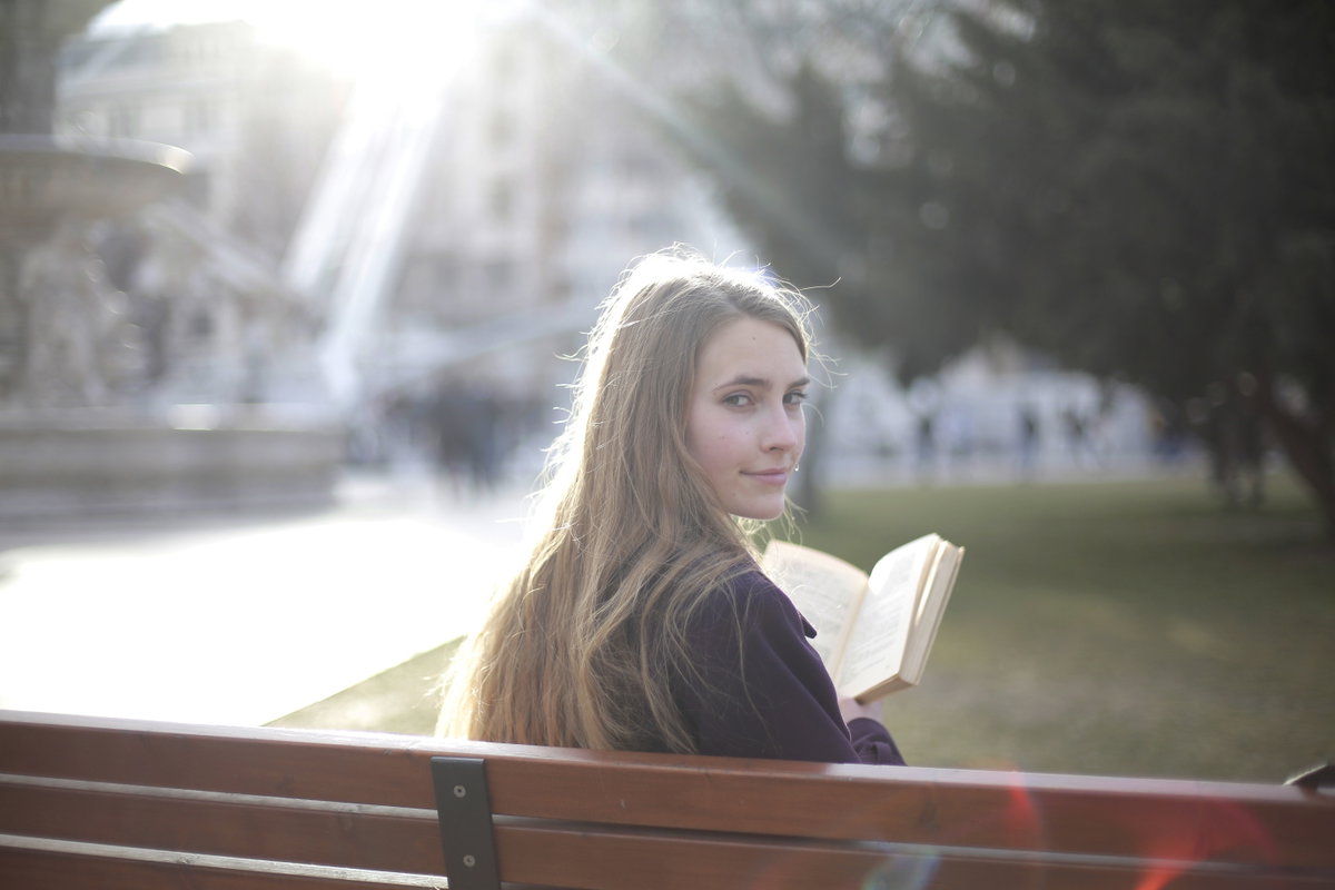 Mädchen auf einer Parkbank mit einem Buch