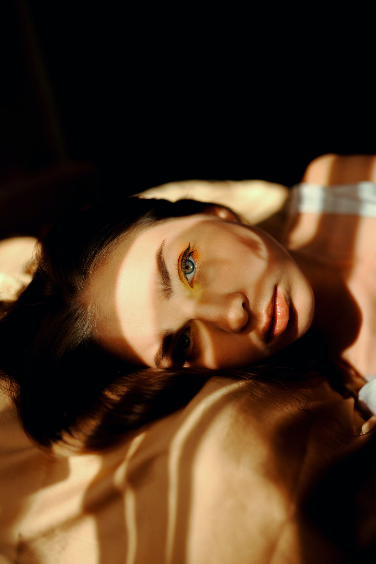 Mädchen liegt auf einem Bett mit Sonnenstrahlen im Gesicht