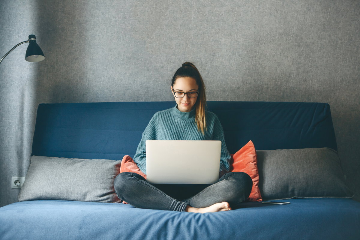Junge Frau sitzt auf dem Sofa mit Laptop